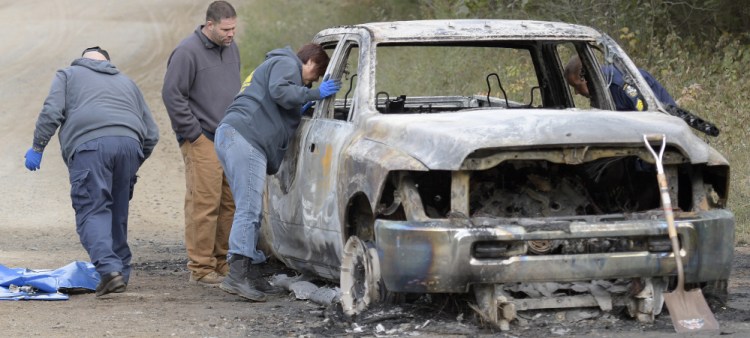 Investigators examine a charred pickup containing a body on Lincoln Street in Richmond on Saturday.