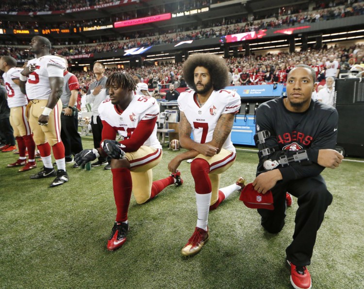 Former San Francisco quarterback Colin Kaepernick, center, and linebacker Eli Harold, left, kneeled to protest racial inequality. 
