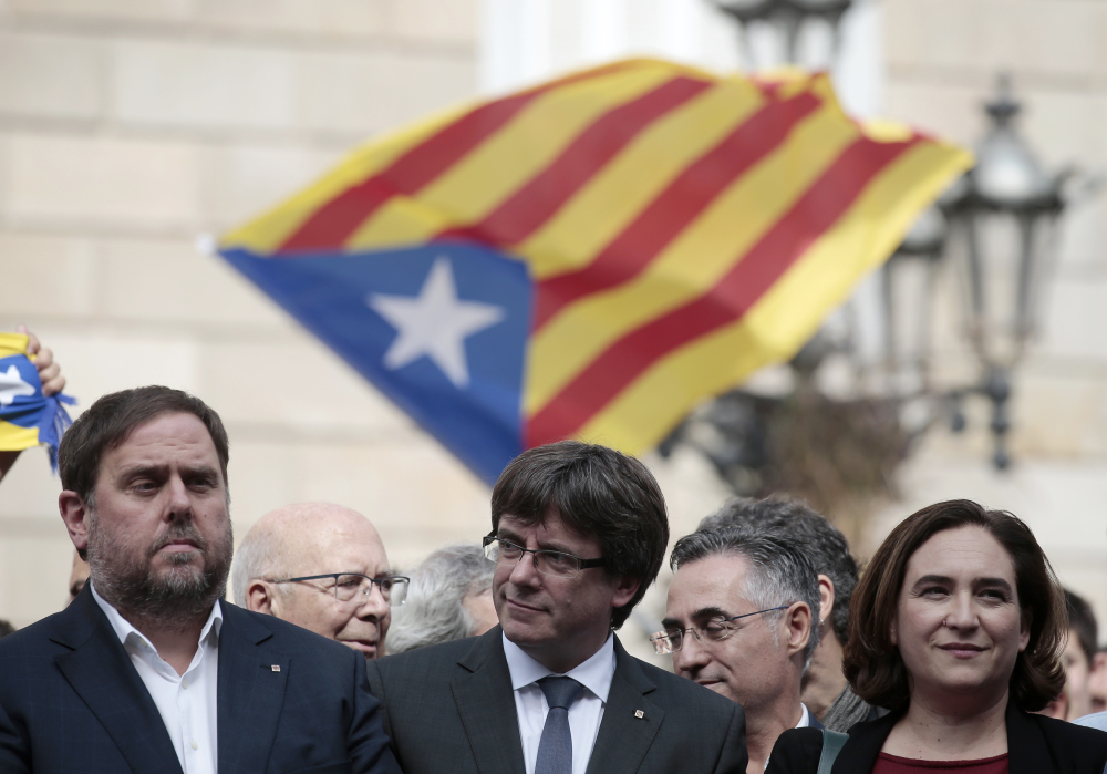 From left, Catalan regional Vice-President Oriol Junqueras, Catalan President Carles Puigdemont and Barcelona Mayor Ada Colau observe a protest called by pro-independence activists in Barcelona, Spain, on Monday. Catalonians voted Sunday in favor of independence.