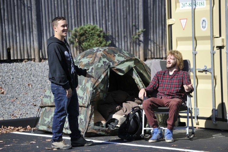Dave Sirois, left, and Matthew Scally, both of Saco, talk while waiting in the parking lot Monday for Tuesday's Krispy Kreme grand opening. The two were fifth and sixth in line and brought a tent to sleep in overnight Monday.