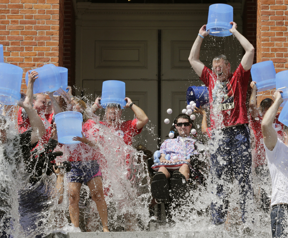 Pete Frates, seated at center in this 2015 photo, helped popularize the ice bucket challenge, which raised roughly $220 million in 2014. The ALS Association received $115 million of that and committed $89 million to research the disease.