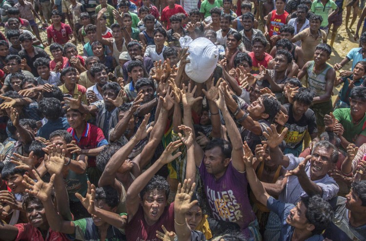 Rohingya Muslims, who crossed over from Myanmar into Bangladesh, stretch their arms out to catch a bag of rice thrown to them during distribution of aid near Balukhali refugee camp. With Rohingya refugees still flooding across the border from Myanmar, those packed into camps and makeshift settlements in Bangladesh are desperate for scant basic resources and fights erupt over food and water.