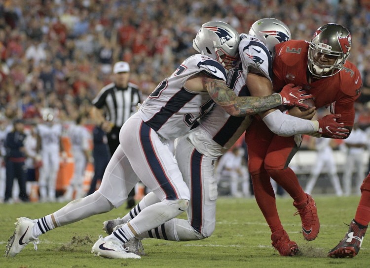Buccaneers quarterback Jameis Winston, right, is hit by New England defenders in the fourth quarter Thursday night at Tampa, Fla. The Patriots won 19-14 but allowed 300-plus yards passing for the fifth straight game.