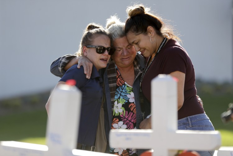 Melissa Gerber, left, Nancy Hardy, center, and Sandra Serralde, all of Las Vegas, embrace Friday as they look on crosses in honor of those killed in the mass shooting Sunday. Investigators still don't know why Stephen Paddock opened fire on thousands of people at the Route 91 Harvest Festival.