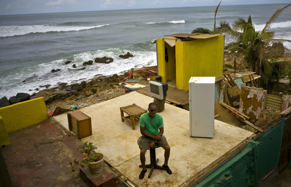 Roberto Figueroa Caballero sits on a small table at the remains of his San Juan, Puerto Rican, home that was destroyed by Hurricane Maria last month.