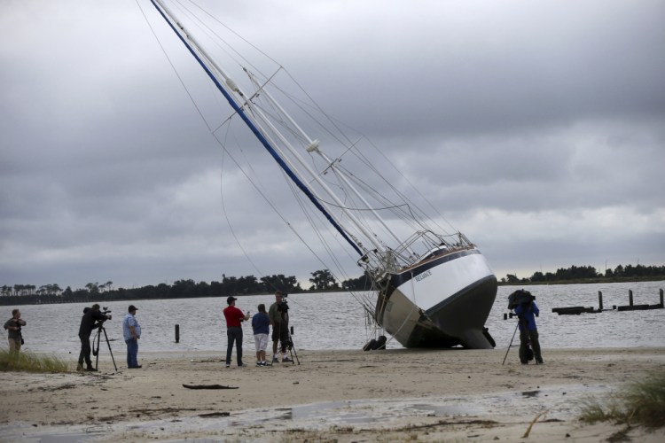 News crews film a sailboat that washed ashore along the Gulf of Mexico in Biloxi, Miss., in the aftermath of Hurricane Nate on Sunday.