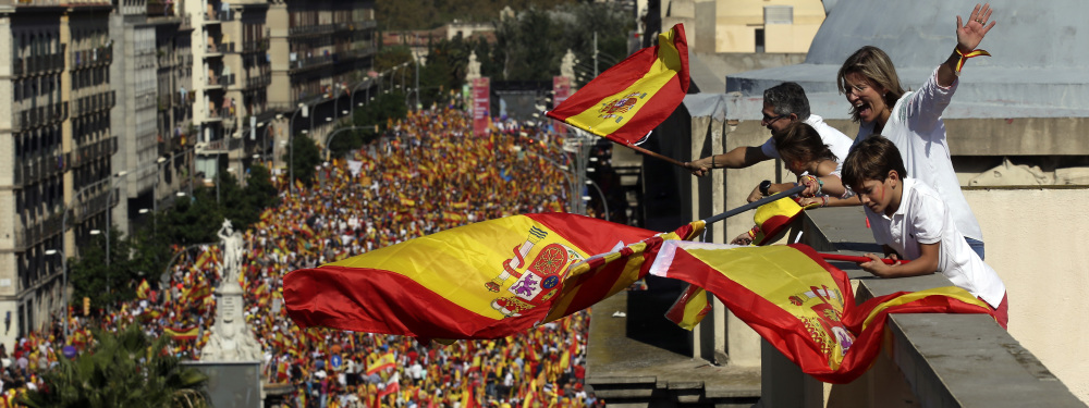People on a rooftop wave Spanish flags during a march in downtown Barcelona, Spain.