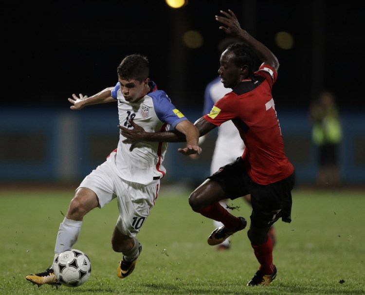 Christian Pulisic of the U.S., left, battles for the ball with Trinidad and Tobago's Nathan Lewis in Tuesday's game in Couva, Trinidad. The U.S. lost 2-1.