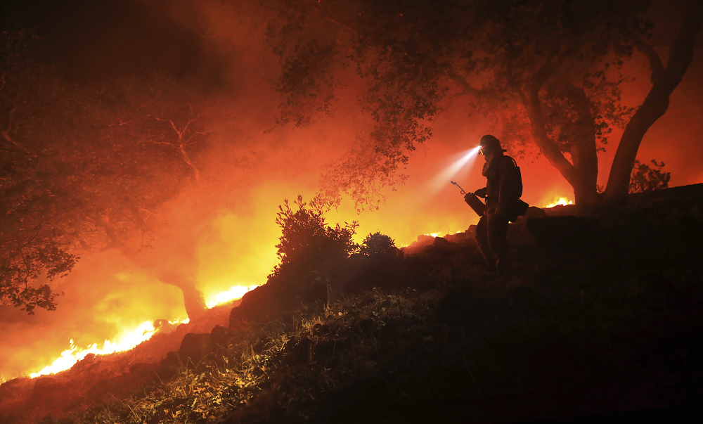 A San Diego Cal Fire firefighter monitors a flare-up on a the head of a wildfire above the Sonoma Valley on Wednesday in Sonoma, Calif. A wind shift caused flames to move quickly uphill and threaten homes in the area.