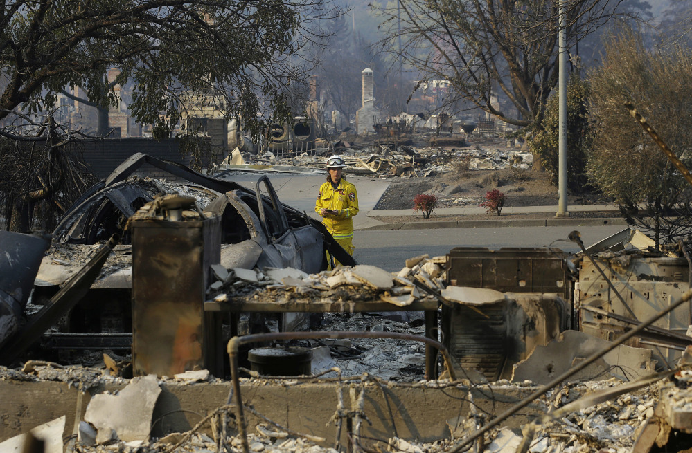 Cal Fire forester Kim Sone inspects damage at homes destroyed by fires in Santa Rosa, Calif., on Thursday. Gusting winds and dry air forecast for Thursday could drive the next wave of devastating wildfires that are already well on their way to becoming the deadliest and most destructive in California history.