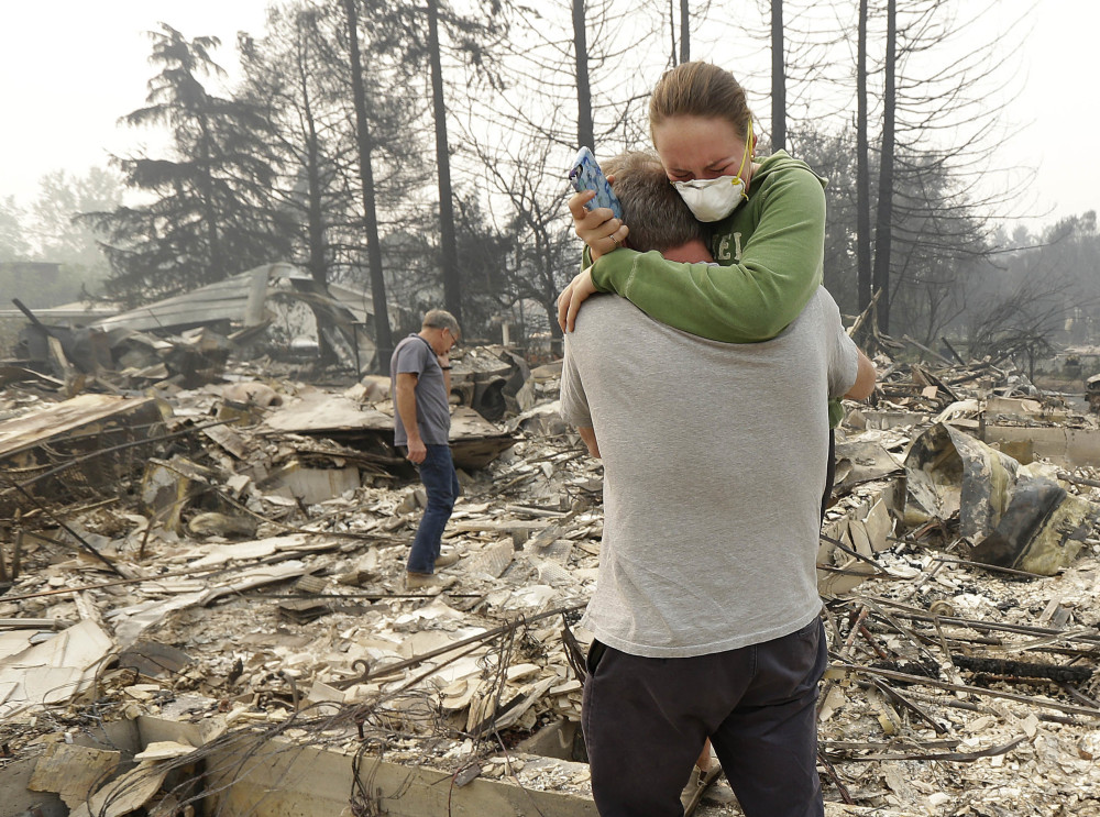 Todd Caughey, left, hugs his daughter Ella as they visit their destroyed home Tuesday in Kenwood, Calif. A fire official said Thursday that "These fires are a long way from being contained."
Associated Press/Jeff Chiu