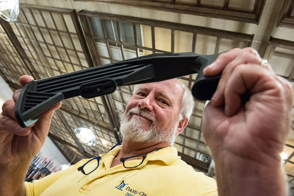 John Reid holds up a bump stock Saturday afternoon at his gun show. He said his shop in Auburn had sold out of the attachments in a couple of days in reaction to talk of a ban.