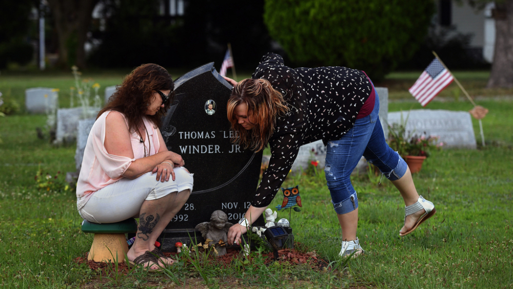 Tina Snyder, left, and Courtney Winder visit the grave of - respectively - their son and brother in July. The 24-year-old died of an opioid overdose in November. Winder lost another brother to an overdose in 2014. Must credit: