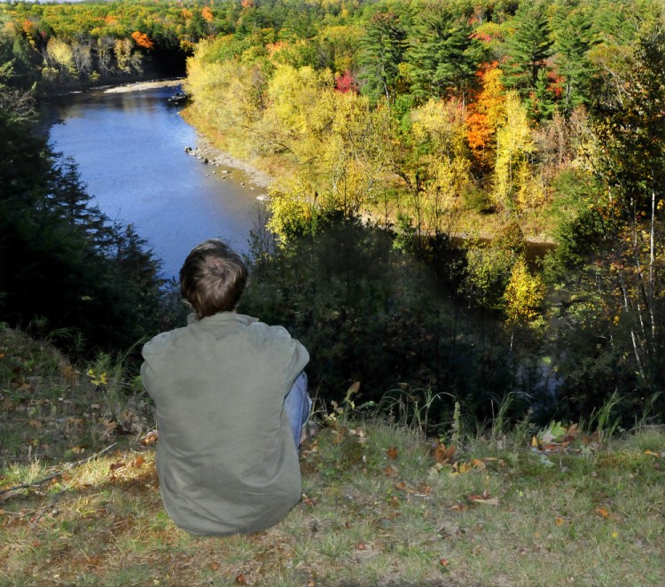 A Mercer resident, who declined to give his name, looks down on the Sandy River from his property Monday. He was rescued Sunday by firefighters from Skowhegan and Norridgewock after the ax he was wielding slipped, cutting him badly on an ankle.