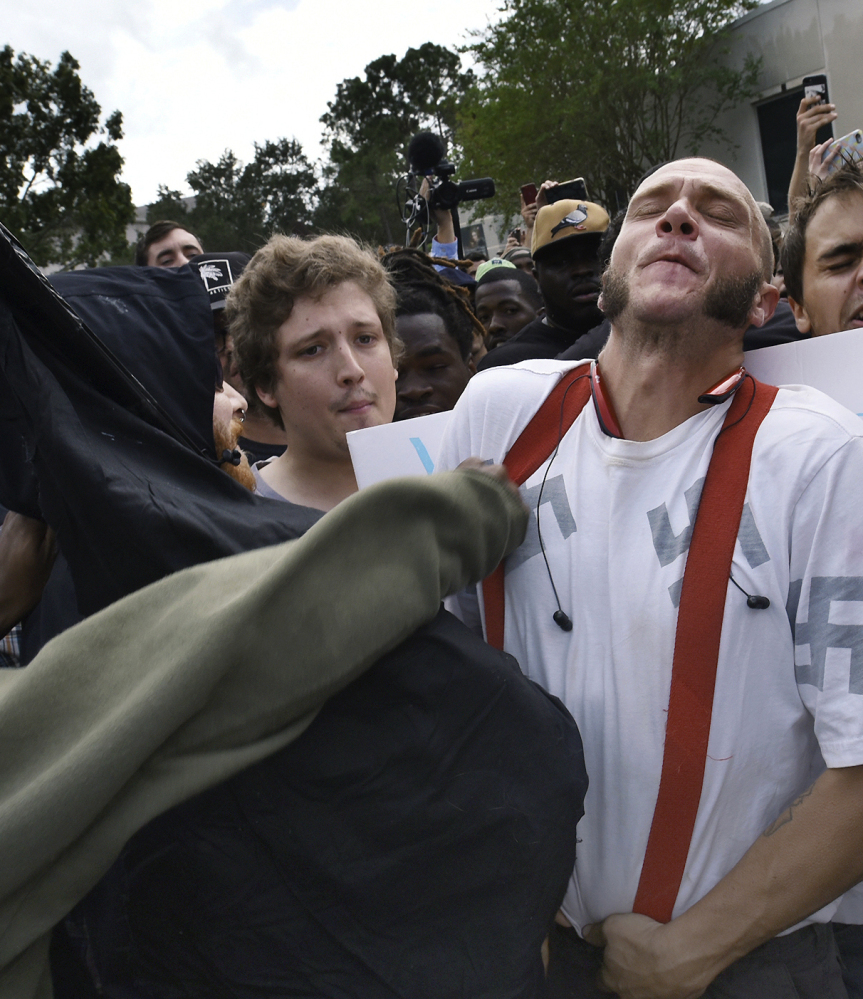 Randy Furniss, left, of Idaho recoils after getting punched in the face as he walks through a crowd of protesters outside a University of Florida auditorium where white nationalist Richard Spencer was preparing to speak Thursday. A supporter of Spencer, right, grabs a protester's tie as opposing groups confront each other.