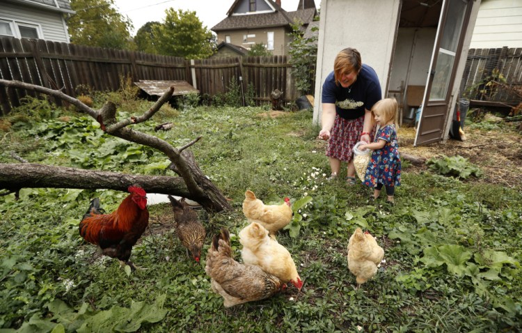 Tanya Keith of Des Moines, Iowa, and her daughter Iolana feed their chickens in the backyard of their home in Des Moines in September.