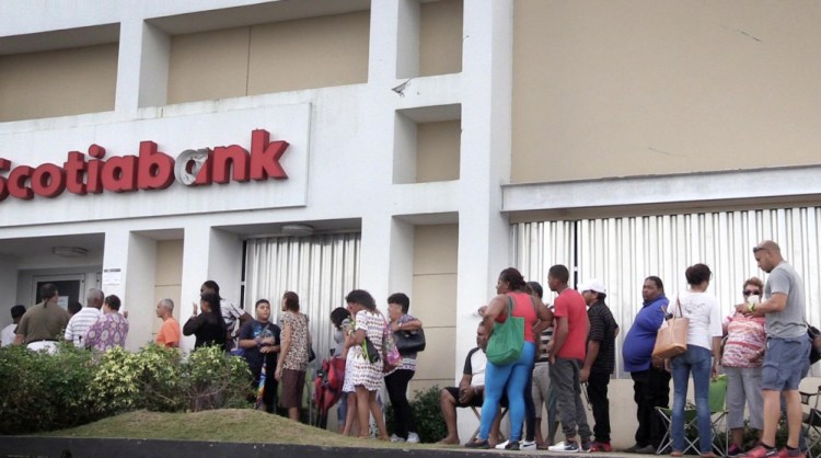 A long line of people waits to enter a branch of Scotia Bank on Saturday in Carolina, Puerto Rico. ATMs and credit cards don't work since there is no electricity and the only way to buy goods is by using cash.