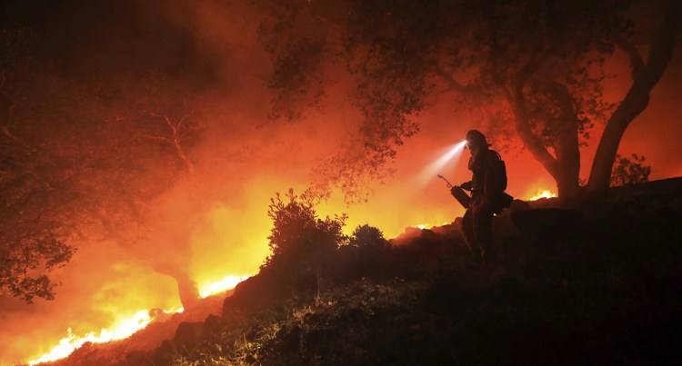 A San Diego firefighter monitors a flare-up on at the head of a wildfire off High Road above the Sonoma Valley on Oct. 11 in Sonoma, Calif. A wind shift caused flames to move quickly uphill and threaten homes in the area. Three days after the fires began, firefighters were still unable to gain control of the blazes that had turned entire Northern California neighborhoods to ash and destroyed thousands of homes and businesses.