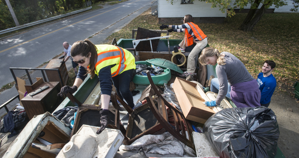 Colby College staff members Laura Jones-Pettit, left, and Katie Sawyer, and Megan Marsh, back, organize a large metal bin of old household and yard goods collected Saturday for a cleanup designed to help students and faculty engage with the city of Waterville.