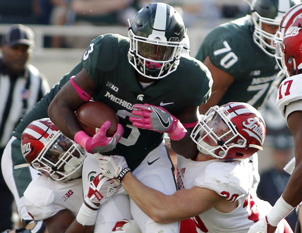 L.J. Scott of Michigan State is stopped by Nathanael Snyder, left, and Chase Dutra of Indiana during the second quarter of 18th-ranked Michigan State's 17-9 victory in a Big Ten game Saturday.
