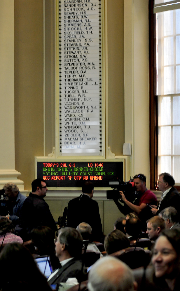 Members of the media assemble beneath a malfunctioning electronic vote tally board, one reason for delays during a special session of the Legislature in Augusta on Monday.
