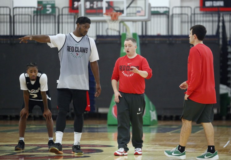 In his first practice as a basketball head coach, Brandon Bailey, center, talks with Devin Williams, one of the 15 players who attended the opening day of training camp Monday for the Maine Red Claws at the Portland Expo.