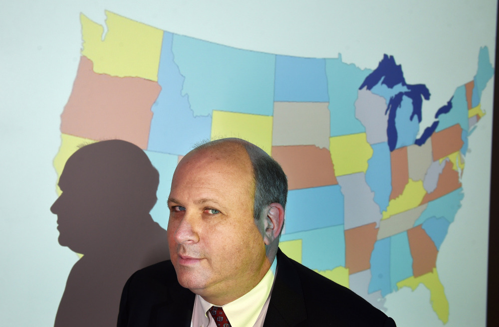 Marc Elias of Perkins Coie poses for a portrait in front of a projected map of the United States at the Washington firm in April 2016.