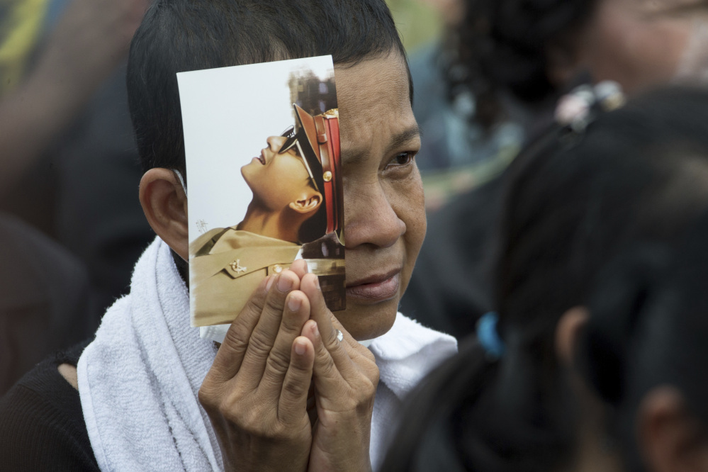 A Thai mourner holds a portrait of King Bhumibol Adulyadej.