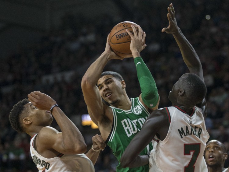 Boston's Jayson Tatum looks to pass the ball after being stopped by Milwaukee's Giannis Antetokounmpo and Thon Maker in the second half Thursday night in Milwaukee.