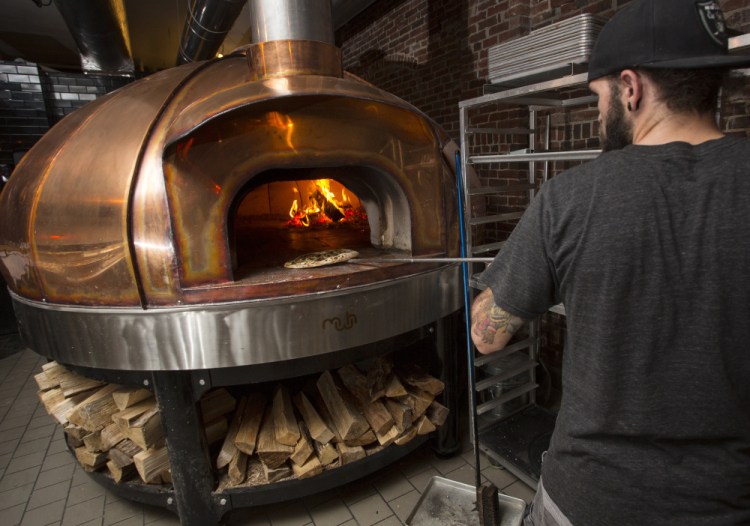 Bradley Foster works the wood-fired Le Panyol oven, the copper surface of which remains cool to the touch even when the temperature of the deck inside hits 750 degrees.