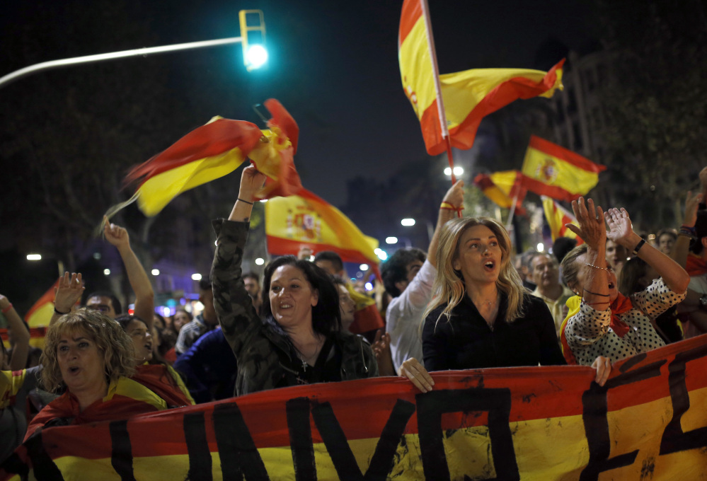 Anti-independence marchers wave Spanish flags as they protest the unilateral declaration of independence approved earlier by the Catalan parliament in Barcelona on Friday.