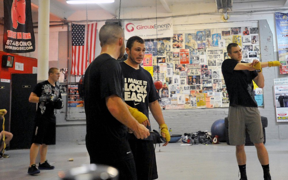 Joel Bishop, center facing, talks with friend Brandon Berry, left center, during a training session at the Portland Boxing Club in Portland on Oct. 1, 2014.