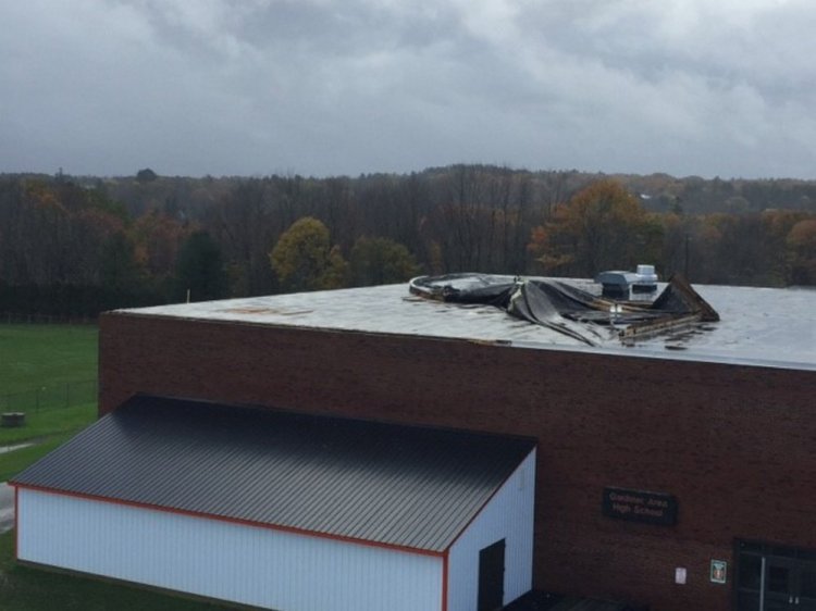 Damage can be seen atop the Gardiner Area High School roof on Monday following a destructive storm that swept through the region.