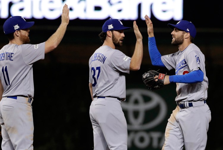 Los Angeles Dodgers' Chris Taylor, right, celebrates with Charlie Culberson (37) and Logan Forsythe (11) after Game 3 of baseball's National League Championship Series against the Chicago Cubs.