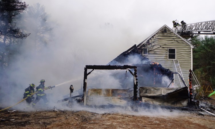 Standish firefighters battle a house fire on Middle Road in Standish on Monday. Standish Fire Chief Rob Caron says that the cause is not known yet but that responding to the fire was difficult because of roads blocked by downed trees.