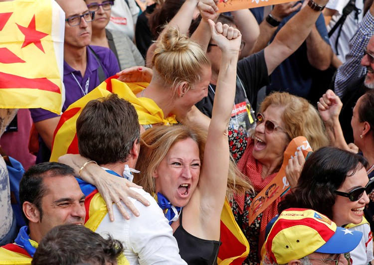 People in Barcelona celebrate as they watch giant screens televising the Catalan regional parliament voting to declare independence from Spain. 