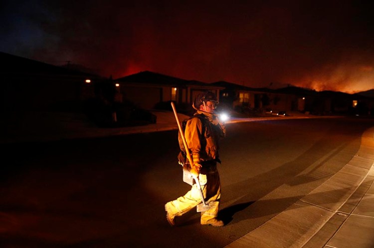A firefighter looks for flammable items in an evacuated residential area as wildfires continue to burn on Saturday.