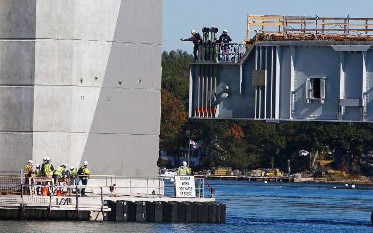 Dana Woods, center, a supervisor for Cianbro, measures for clearance from the span back to the bridge tower as the span is positioned for attaching to the Sarah Mildred Long Bridge between Kittery and Portsmouth, N.H. 