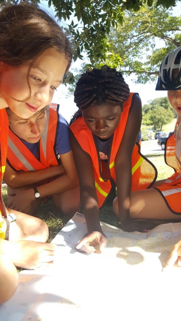 Ainsley Judge, second left, looks on as Calia Brown, Orlane Zouri and Cora Johnson map out a bicycle route at Girls Mountain Bike Camp, a Bike School program, over the summer.