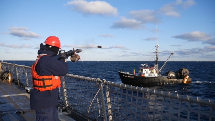 Petty Officer 3rd Class Anderson Ernst uses a line throwing gun to help pass the tow line to the 65-foot fishing troller, Black Beauty, on Saturday off the coast of New Hampshire. Coast Guard cutter Campbell, homeported in Kittery, Maine, towed the vessel to Gloucester, Massachusetts. 