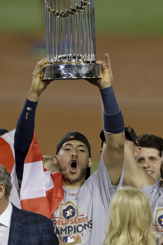 The Houston Astros' Carlos Correa celebrates with the trophy after their win against the Los Angeles Dodgers in Game 7 of baseball's World Series Wednesday, Nov. 1, 2017, in Los Angeles. The Astros won 5-1 to win the series 4-3. (AP Photo/Alex Gallardo)