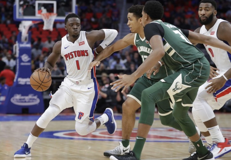 Reggie Jackson of the Detroit Pistons looks for room as Malcolm Brogdon, center, and John Henson of the Milwaukee Bucks move in to defend Friday night during the first period of the Pistons' 105-96 victory at home.