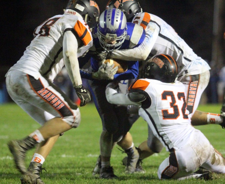 Lawrence running back Isaiah Schooler is brought down by Brunswick's Bailey Pelletier, left, Sam Dorval, back, and Jack Harvey.