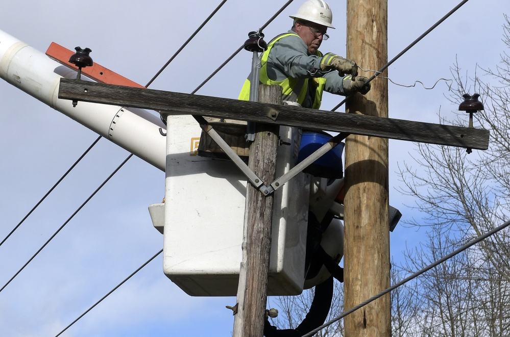 Central Maine Power Co. lineman Wayne Piper unhooks a pole Monday after it snapped on South Monmouth Road in Monmouth. Response to storm damage has earned praise, owing in part to lessons learned from the Ice Storm of 1998.