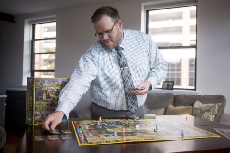 Tom Deschenes sets up the board game he invented, Quest for the Antidote, at his apartment in Portland. It took him five years to create and design the game.