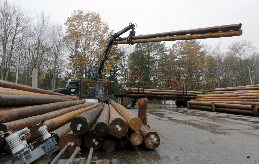 Workers at Central Maine Power scramble to move utility poles and transformers from its stockyard in Brunswick.