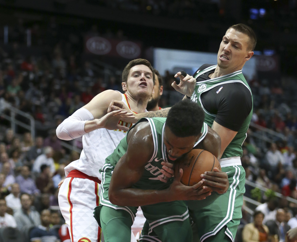 Celtics guard Jaylen Brown grabs a rebound as Atlanta forward Luke Babbitt and Boston forward Daniel Theis also battle for the ball.