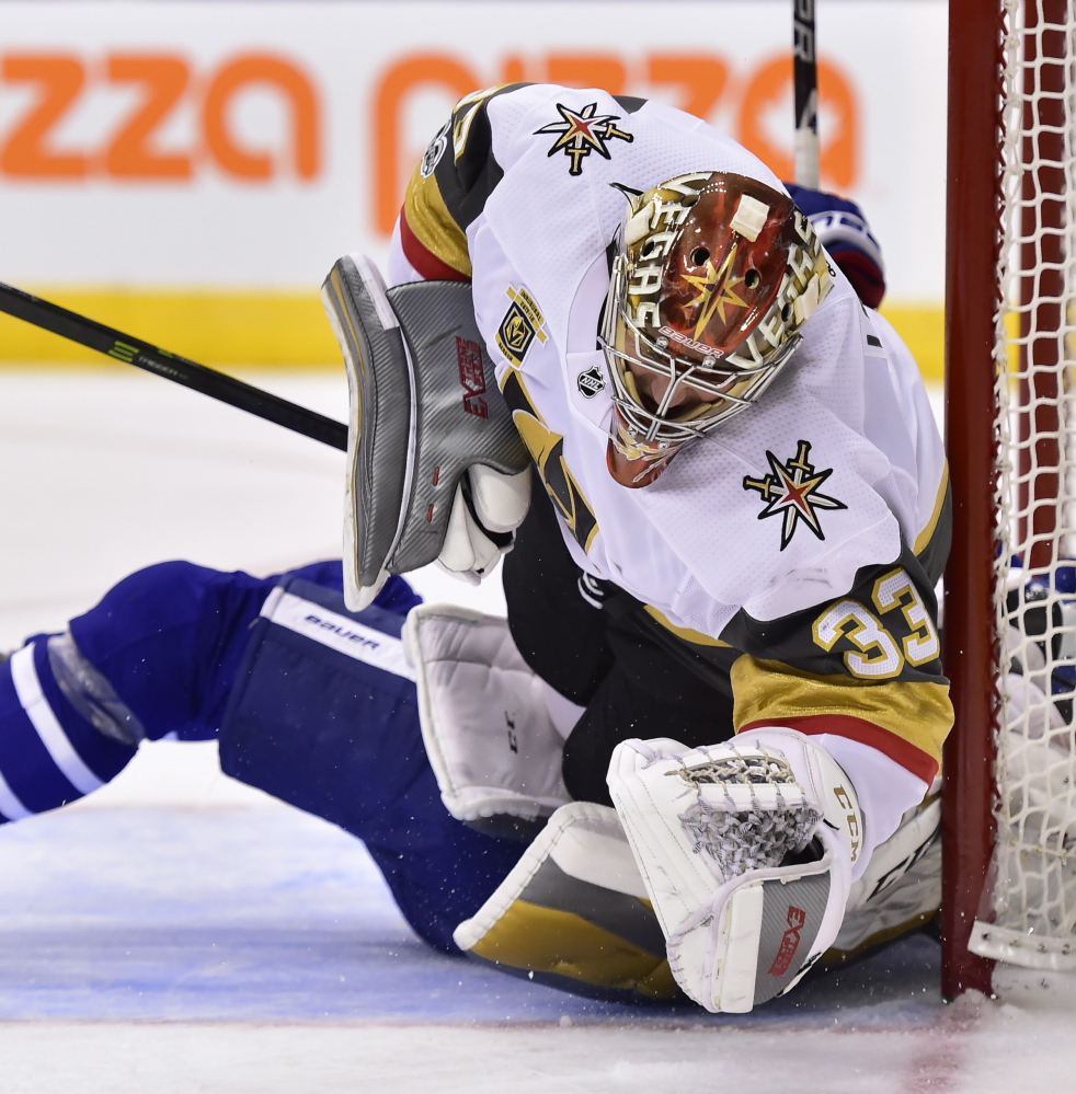 Vegas Golden Knights goalie Maxime Lagace is run over by Maple Leafs forward Zach Hyman, obscured, during the second period of Toronto's 4-3 shootout win at home Monday.