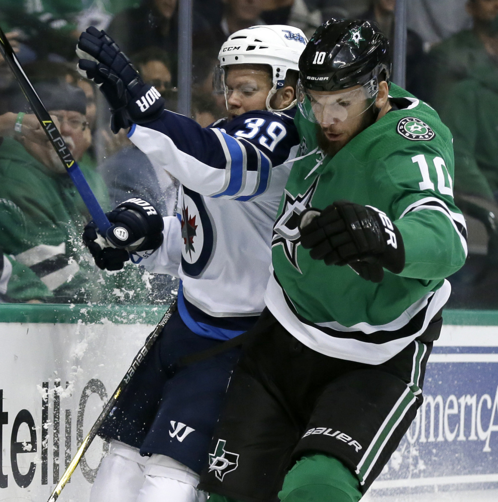 Winnipeg defenseman Toby Enstrom and Dallas center Martin Hanzal slam against the boards chasing a loose puck in the first period Monday night in Dallas.