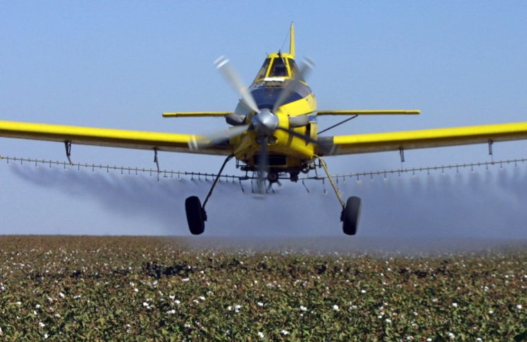 A plane dusts cotton crops in Lemoore, Calif. A new rule announced Tuesday makes spraying certain pesticides within a quarter mile of a school a fine-able offense.